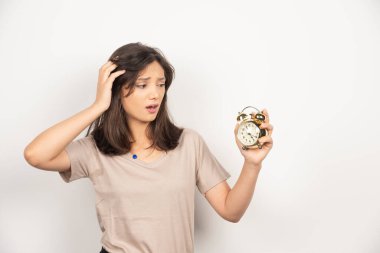 Beyaz arka planda çalar saati tutan genç bir kadın. Yüksek kalite fotoğraf