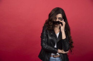 Kırmızı arka planda siyah gözlüklü genç bir kadın. Yüksek kalite fotoğraf