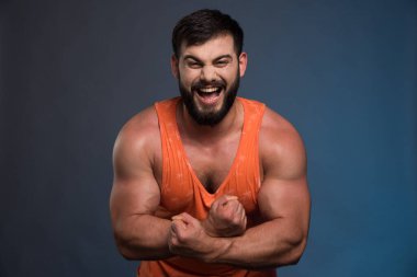 Sporcu koyu mavi arka planda kaslarını gösteriyor. Yüksek kalite fotoğraf