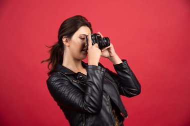 Siyah deri ceketli, elinde profesyonel kamerasıyla güzel fotoğraflar çeken havalı bir kız. Yüksek kalite fotoğraf