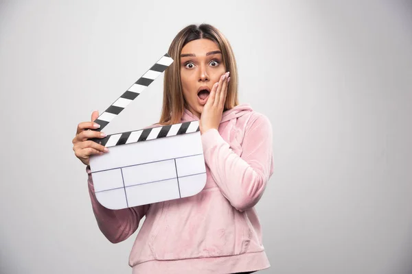 Blond Lady Pink Sweatshirt Holding Blank Clapper Board Looks Surprized — Stock Photo, Image