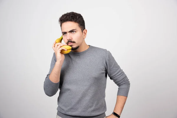 バナナを携帯電話として持つ若い男モデル 高品質の写真 — ストック写真