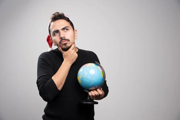 Bedachtzame Man Hoed Van Kerstman Poserend Met Wereldbol Hoge Kwaliteit — Stockfoto