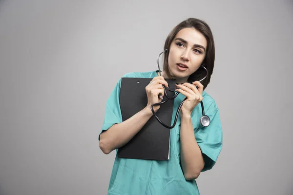 Médico Femenino Usando Estetoscopio Sobre Fondo Gris Foto Alta Calidad — Foto de Stock