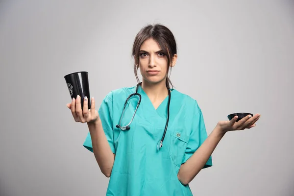 灰色の背景にコーヒーカップを保持する女性医師 高品質の写真 — ストック写真