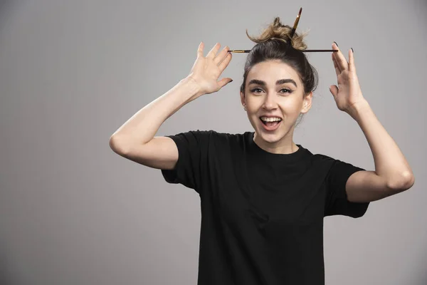 Young woman with messy bun posing on gray background. High quality photo