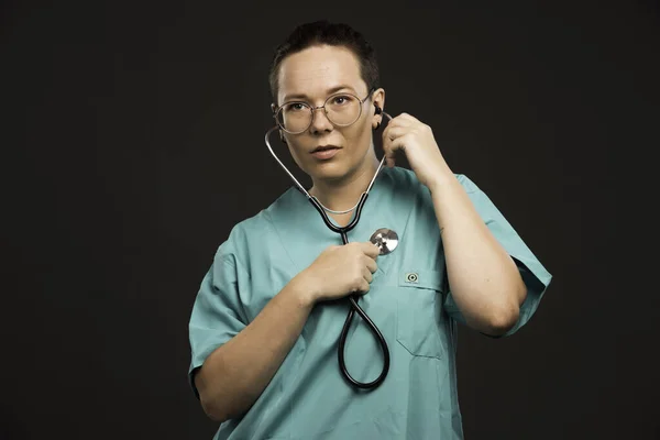 聴診器を持った緑色の制服を着た女性医師が心臓の鼓動を確認する 高品質の写真 — ストック写真