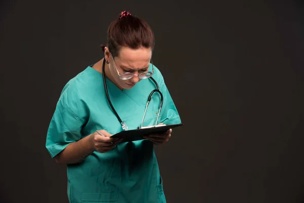 緑色の制服を着た女性看護師が空白を保持し 読もうとします 高品質の写真 — ストック写真