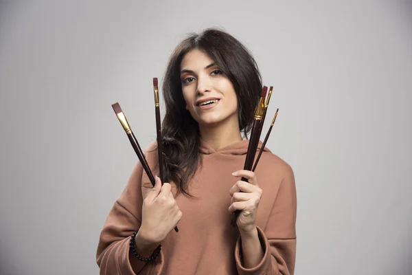 Jovem Segurando Pincéis Tinta Fundo Cinza Foto Alta Qualidade — Fotografia de Stock