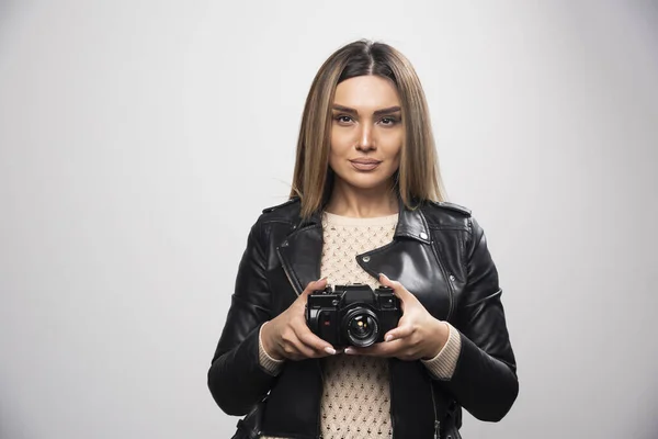 黒の革のジャケットの若い女性は カメラと真剣に 専門的な方法で写真を撮る 高品質の写真 — ストック写真