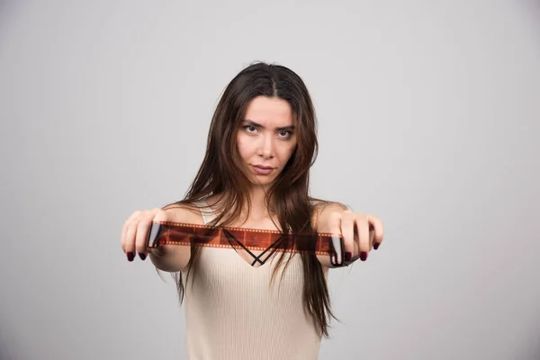 Mujer Pelo Largo Mostrando Película Cámara Sobre Fondo Gris Foto — Foto de Stock