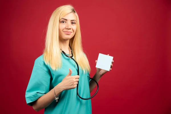 Blonde doctor with stethoscope and memo pad giving thumbs up. High quality photo