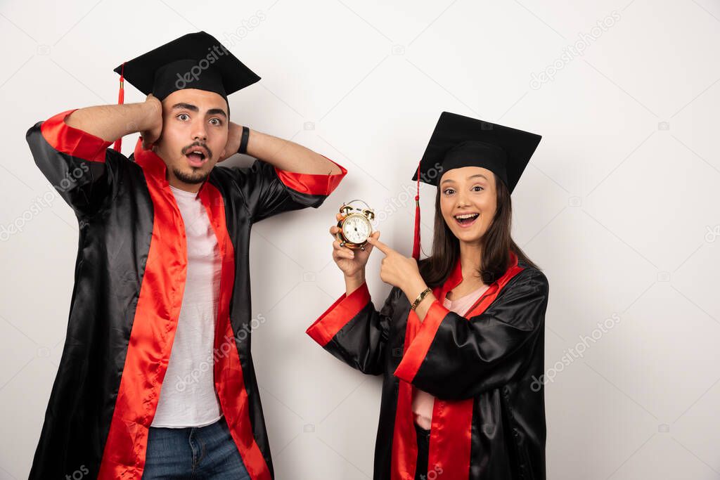 Fresh graduates in gown showing time on white background. High quality photo