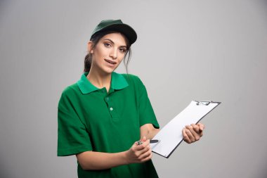 Yeşil üniformalı teslimatçı kadın nereyi imzalayacağını gösteriyor. Yüksek kalite fotoğraf