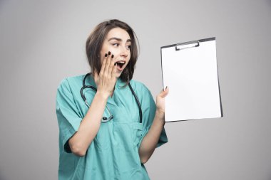 Gri arka planda pano gösteren sürpriz bir doktor. Yüksek kalite fotoğraf