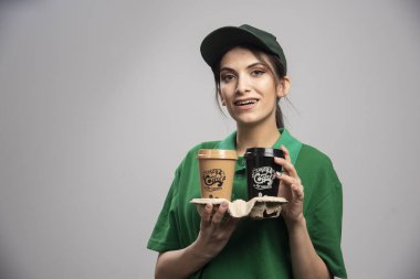 Teslimatçı kadın elinde kahveyle ayakta duruyor. Yüksek kalite fotoğraf