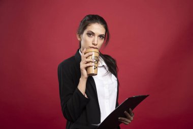 Kırmızı arka planda kahve içen genç bir iş kadını. Yüksek kalite fotoğraf