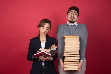 Elinde bir yığın kitap tutan genç bir adam ve okuyan genç bir kadın. Yüksek kalite fotoğraf