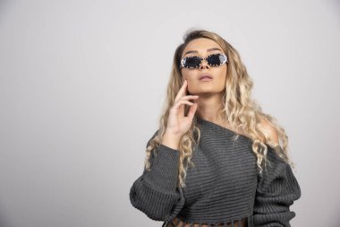 Gri arka planda duran gözlüklü genç bir kadın. Yüksek kalite fotoğraf