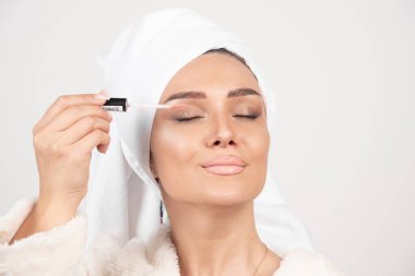 Bornozlu genç bir kadın göz kapaklarına ruj sürüyor. Yüksek kalite fotoğraf