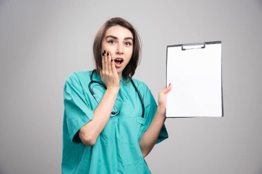 Gri arka planda pano gösteren sürpriz bir doktor. Yüksek kalite fotoğraf