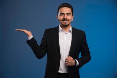 Siyah takım elbiseli bir iş adamı bir şeylerin reklamını yapıyor. Yüksek kalite fotoğraf