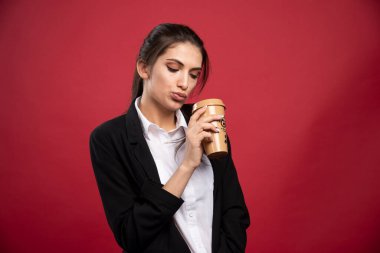 Kırmızı arka planda kahve içen genç bir iş kadını. Yüksek kalite fotoğraf
