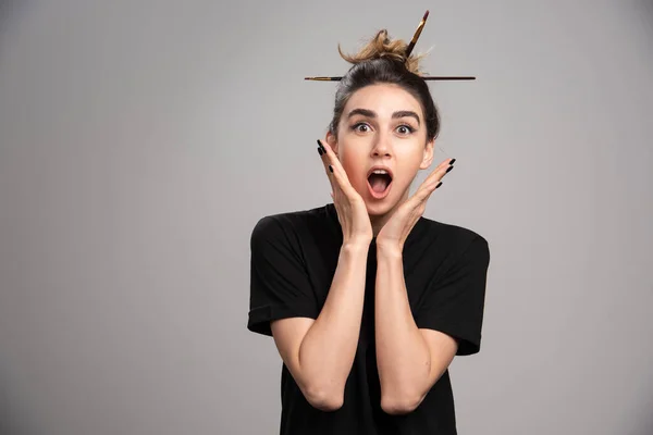 Surprised woman with messy bun posing on gray background. High quality photo