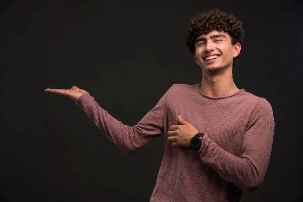 Jovem Com Penteado Encaracolado Apresentando Algo Foto Alta Qualidade — Fotografia de Stock