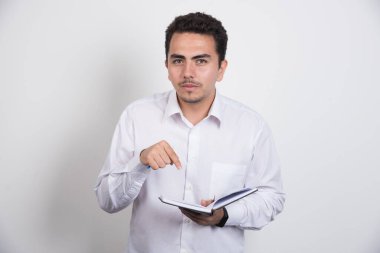 Esmer iş adamı beyaz arka plandaki defteri işaret ediyor. Yüksek kalite fotoğraf