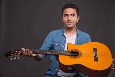 Gitarist karanlık arka planda gitar tutuyor. Yüksek kalite fotoğraf