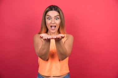 Güzel genç bayan ellerini şaşırtıcı bir şekilde kırmızı arka planda gösteriyor. Yüksek kalite fotoğraf