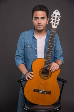Esmer adam, elinde gitarla poz veriyor. Yüksek kalite fotoğraf