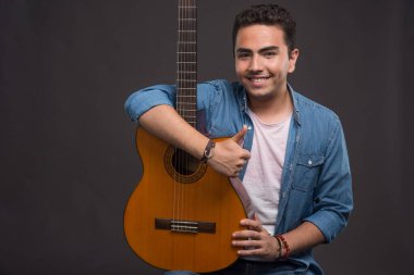 Gitarist karanlık arka planda gitar tutuyor. Yüksek kalite fotoğraf