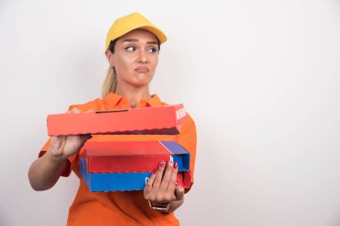 Pizza teslimatçısı kadın beyaz arka planda pizza kutuları tutuyor ve sıkılmış bir ifade takınıyor. Yüksek kalite fotoğraf