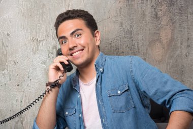 Genç adamın telefonla konuşurken ve sandalyede otururken çekilmiş bir fotoğrafı. Yüksek kalite fotoğraf