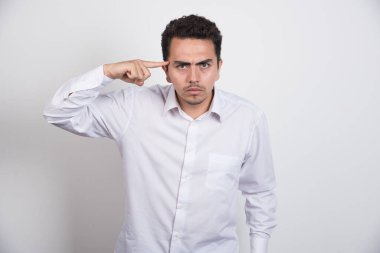 Ciddi bir adam beyaz arka planda kafasını işaret ediyor. Yüksek kalite fotoğraf