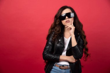 Kırmızı arka planda siyah gözlüklü genç bir kadın. Yüksek kalite fotoğraf