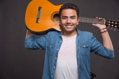 Arka planda gitarla poz veren genç adam. Yüksek kalite fotoğraf