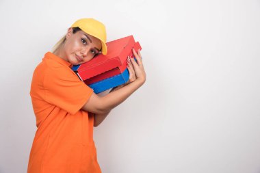 Pizza teslimatçısı kadın elinde iki eliyle beyaz arka planda pizza kutuları tutuyor. Yüksek kalite fotoğraf