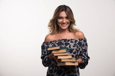 Beyaz arka planda gülerken kitapları tutan genç bir kadın. Yüksek kalite fotoğraf