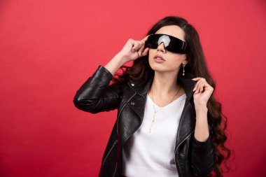 Kırmızı arka planda siyah gözlüklü genç bir kadın. Yüksek kalite fotoğraf