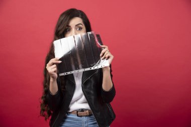 Elinde kırmızı arka planda fotoğraf kaseti olan bir dosya tutan genç bir kadın. Yüksek kalite fotoğraf