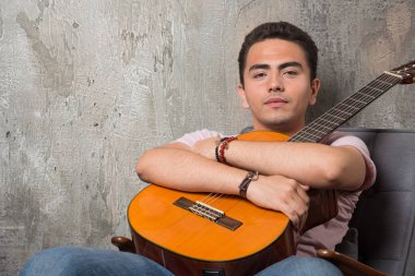 Elinde gitarla kameraya poz veren yakışıklı bir genç. Yüksek kalite fotoğraf