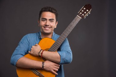 Karanlık arka planda gitarı tutan mutlu adam. Yüksek kalite fotoğraf