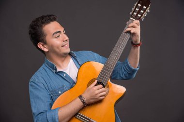 Siyah arka planda gitar çalan genç bir müzisyen. Yüksek kalite fotoğraf