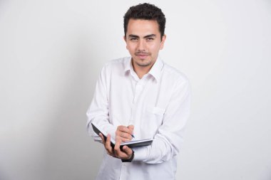 Beyaz arka planda kalemle defter yazan bir iş adamı. Yüksek kalite fotoğraf