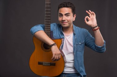 Elinde gitar tutan ve arka planda 