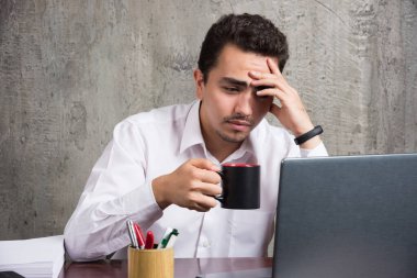 Ofis masasında çay içen bir iş adamı yorgun hissediyor. Yüksek kalite fotoğraf