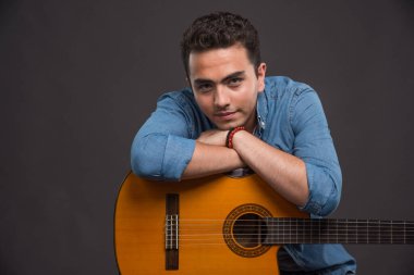 Gitarlı genç adam karanlık arka planda poz veriyor. Yüksek kalite fotoğraf
